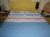 Colcha de cama em tecido com ponto cruz.
